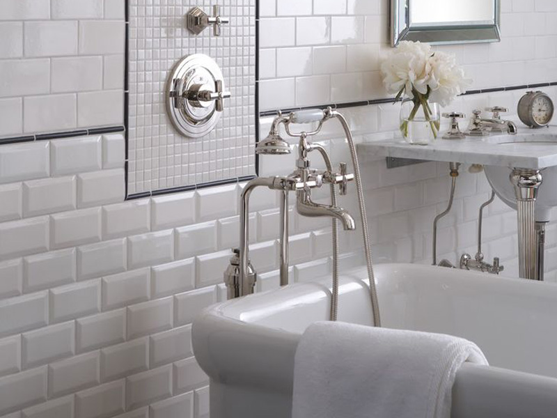 Brilliant faucet บนพื้นหลังของกำแพงสีขาวทำจากกระเบื้องหมูป่า